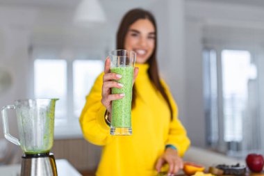 Elinde bir bardak meyve püresi tutan genç bir kadın. Vitaminlerle dolu enerjik bir içeceği nallayan güzel bir kadın. Çiğ gıda diyeti, vejetaryen beslenme, organik detoks yemeği.