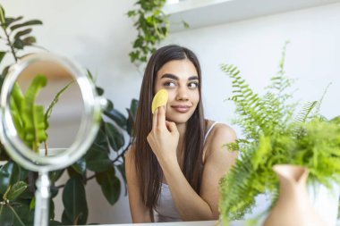 Yakından güzel bir kadın duştan sonra yüz masajı yapıyor. Gülümseyen güzel bayan, pürüzsüz cilt, günlük sabah rutini konsepti.