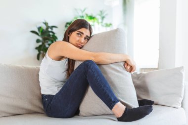 Depresyondan yastığa sarılan ve evde kanepede ağlayan genç bir kadın. Yalnız milenyum hanımı kendini stresli ve umutsuz hissediyor ruh hali bozukluğundan ya da psikolojik problemden muzdarip.