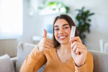 Close-up shot of woman's hand holding a negative test device. Happy young woman showing her negative Coronavirus - Covid-19 rapid test. Focus is on the test.Coronavirus clipart