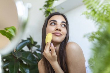 Yakından güzel bir kadın duştan sonra yüz masajı yapıyor. Gülümseyen güzel bayan, pürüzsüz cilt, günlük sabah rutini konsepti.