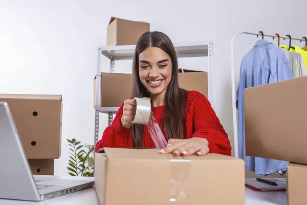 Female online store small business owner. Seller packing box and preparing for delivery. Young woman feeling happy. Packing goods for delivery to customer. Online selling