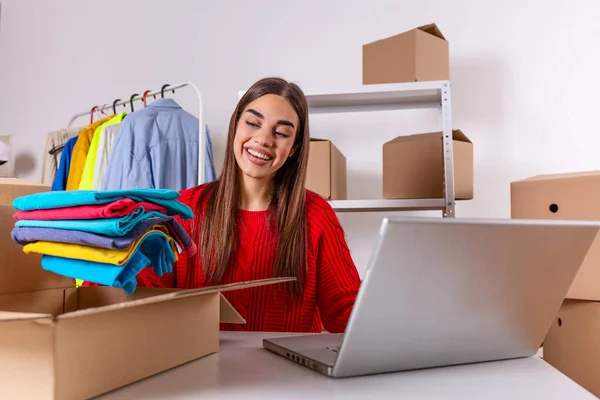 Woman packing item that she sells online. Working woman at online shop. She wearing casual clothing and checking on laptop address of customer and package information. small owner business