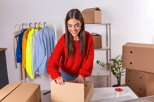 Female online store small business owner. Seller packing box and preparing for delivery. Young woman feeling happy. Packing goods for delivery to customer. Online selling
