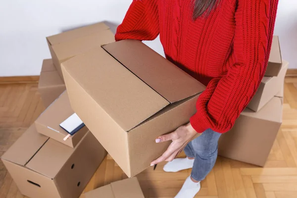 Young woman moving in into new apartment. House moving concept. Woman holding box.