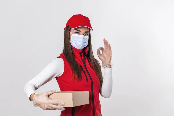 Delivery woman employee in red cap blank t-shirt uniform face mask gloves hold empty cardboard box isolated on white background studio Service quarantine pandemic coronavirus virus 2019-ncov concept