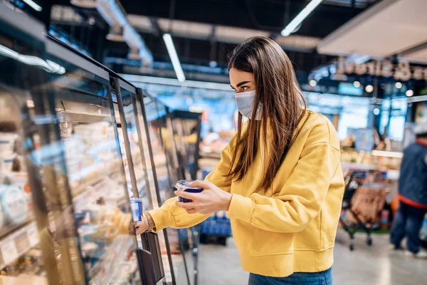 スーパーで顔マスクを身に着けている女性 コロナウイルスCovid 19パンデミック中のパニックショッピング サプライストアでの予算の購入 冷凍スマート購入家庭のパン屋食料品を購入 — ストック写真
