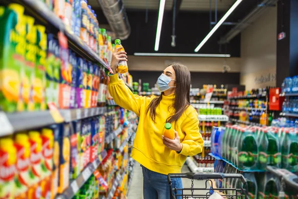 Covid-19 salgını sırasında marketten alışveriş yapan maskeli bir kadın. Alışveriş arabalı bir kadın süpermarketten yiyecek alıyor..