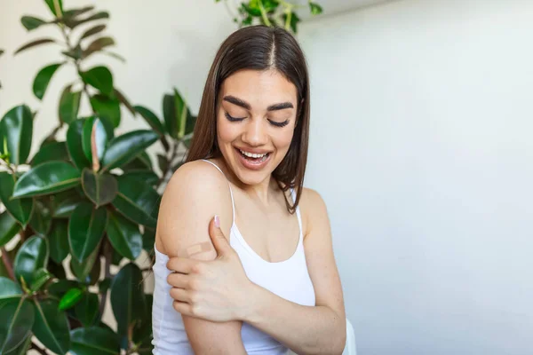 Woman pointing at his arm with a bandage after receiving the covid-19 vaccine. Young woman showing her shoulder after getting coronavirus vaccine