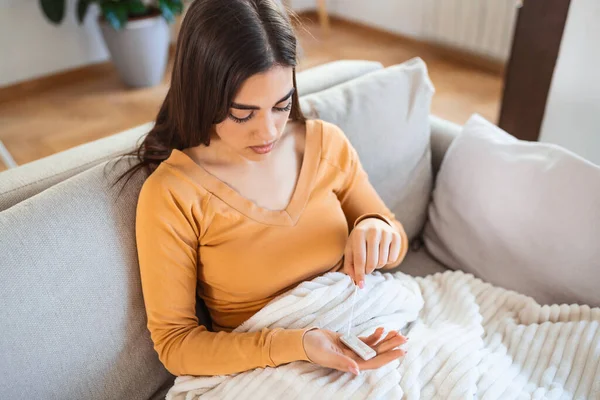 woman using cotton swab while doing coronavirus PCR test at home. Woman using coronavirus rapid diagnostic test. Young woman at home using a nasal swab for COVID-19.