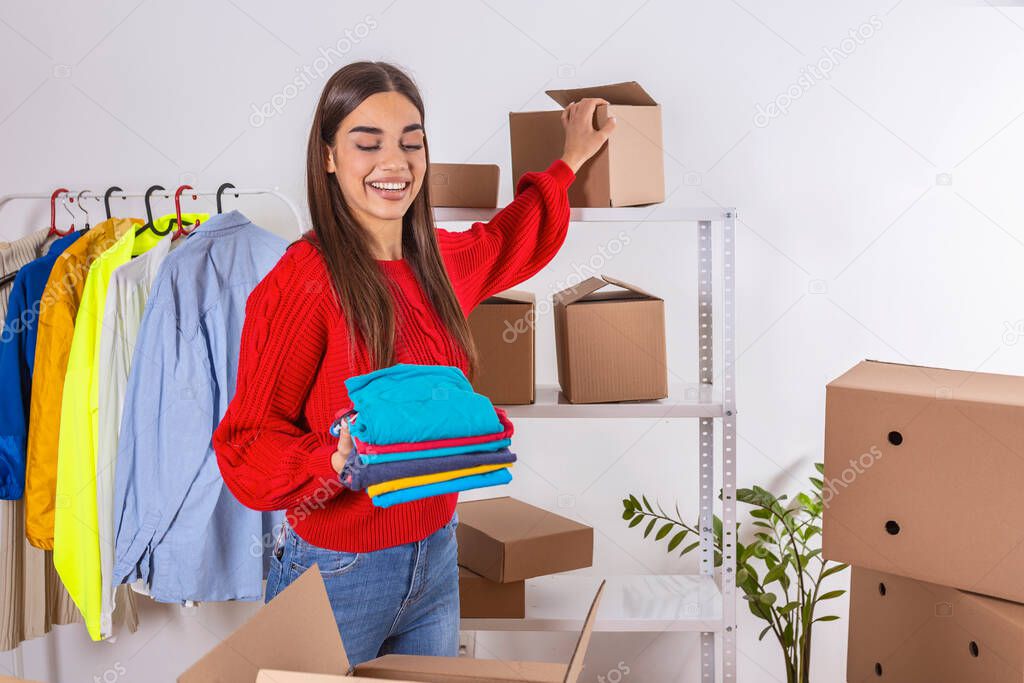 Young woman,small business owner holding items and taking box for packing. Beautiful woman selling online. Online small business owner.