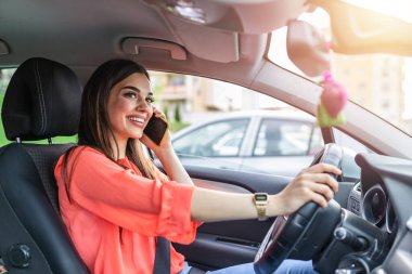Businesswoman driving car and talking on cell phone concentrating on the road. Driving while holding a mobile phone cell phone use while driving. Woman In Car Talking On Mobile Phone Whilst Driving