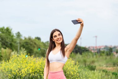 Beautiful young woman running in the city race taking a selfie, Young woman making selfie while taking fitness exercises
