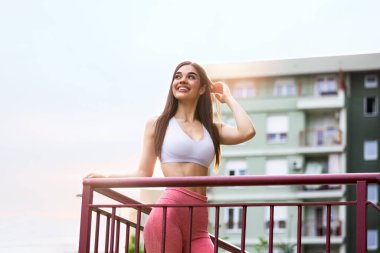 Young sporty woman getting ready to exercise.Woman Doing Workout Exercises On Street. Beautiful Athletic Fit Girl Stretching And Relaxing After Fitness Training