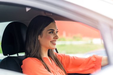 Cute young lady happy driving car. Image of beautiful young woman driving a car and smiling. Portrait of happy female driver steering car with safety belt
