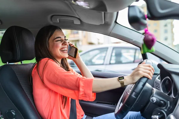 Businesswoman driving car and talking on cell phone concentrating on the road. Driving while holding a mobile phone cell phone use while driving. Woman In Car Talking On Mobile Phone Whilst Driving