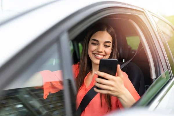 Nice beautiful young woman smile and use mobile phone touching the screen inside the car while travel. modern concept of search hings and contact friends when you are away. daily use of smartphone