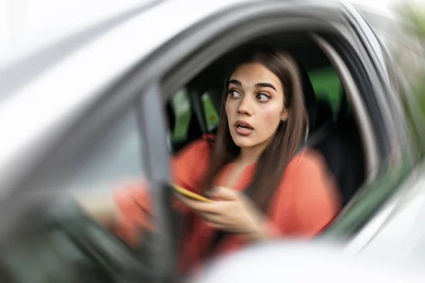 Texting and driving, behind the wheel. Breaking the law. Woman driving car distracted by her mobile phone causing an accident