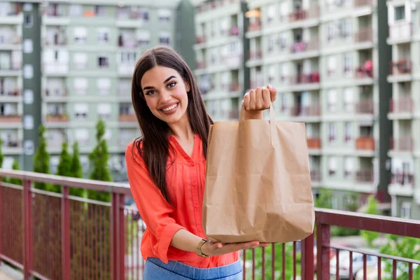 Woman Doing Shopping For Senior Neighbors. Young beautiful woman holding take away paper bag from delivery