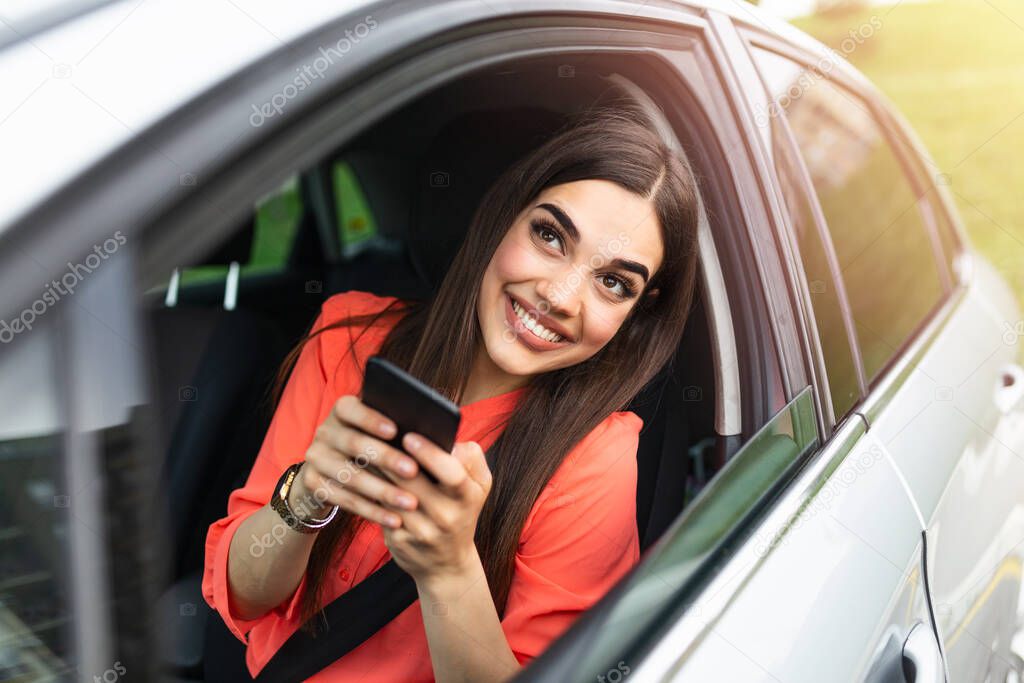 Woman driver using a smart phone in car. Woman driver using a smart phone in car. Leisure, road trip, technology, travel and people concept - Happy woman driving car with smartphone