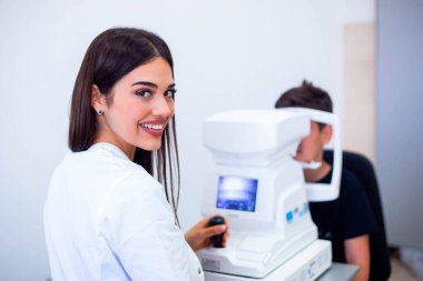 Kadın okulist klinikte göz görme kontrol etmek için makine kullanarak. Küçük çocuk ekipman ve optik mağazada Doktor test göz öğrenciye bakıyor. Göz bakımı ve sağlık konsepti