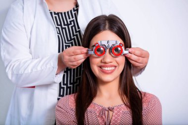 Optometrist deneme çerçevesi ile kadın muayene Oftalmolog. kadın hasta Oftalmolojik klinikte vizyonu kontrol etmek.