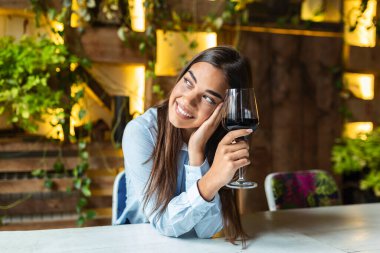 Beautiful woman tasting wine while sitting in restaurant. Image of cute pretty young woman sitting in cafe holding glass and drinking wine. portrait of a beautiful wine tasting tourist woman.