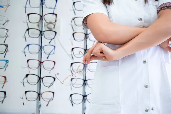 眼科で魅力的な若い女医の画像をトリミングしました 医師眼科医が異なる眼鏡と棚の近くに立っては — ストック写真