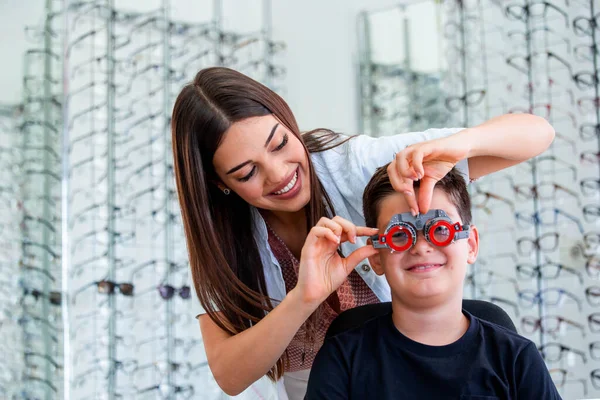 眼科医の試験フレームを持つ魅力的な眼科医がYougの少年を調べる 眼科クリニックで視力をチェックする子供の患者 — ストック写真