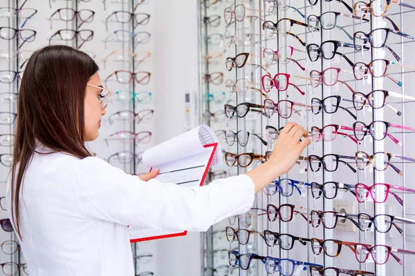 魅力的な女性眼科医がクリップボードにデータを書き込み 光学店で働いています ヘルスケアと医療の概念 — ストック写真