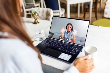 Back view of girl relax in the restaurant talk on video call with smiling sister or friend on quarantine, young woman have fun chat communicate online use Webcam conversation on modern laptop