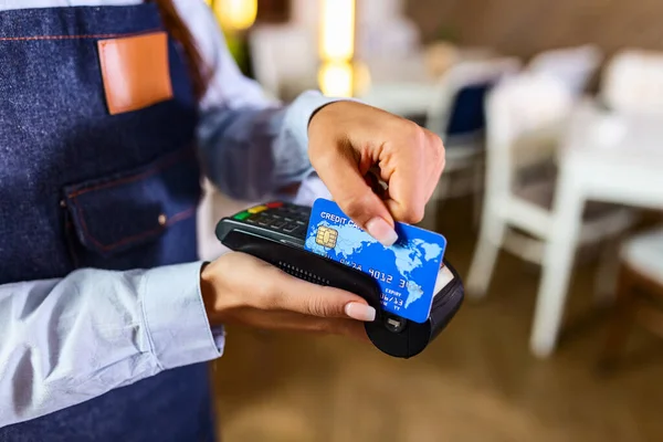 Contactless payment concept, female holding credit card near nfc technology on counter, client make transaction pay bill on terminal rfid cashier machine in restaurant store, close up view