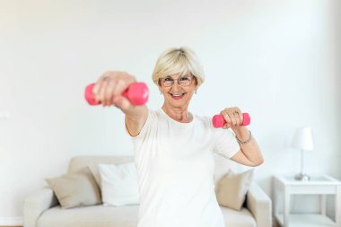 Senior woman exercise with dumbbells at home . happy mature woman doing arm workout using dumbbells. Elderly woman prefers healthy lifestyle