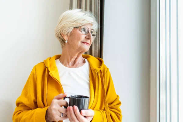 Ανώτερη Γυναίκα Στο Παράθυρο Κρατώντας Ένα Φλιτζάνι Καφέ Τσάι Ηλικιωμένη — Φωτογραφία Αρχείου