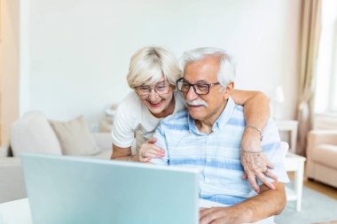 Elderly spouses at home. Wife hugs husband.Having pleasant conversation chatting with grown up children and grandchildren using wireless tech concept