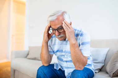 Attack of the monster migraine. Unhappy Retired Senior man holding his head with pain expression . Face of senior man suffering from headache