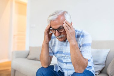Attack of the monster migraine. Unhappy Retired Senior man holding his head with pain expression . Face of senior man suffering from headache