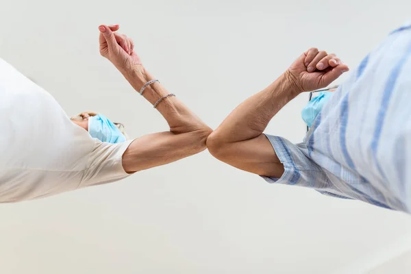 A close-up photo of elbow bumping. Elbow greeting to avoid the spread of coronavirus COVID-19 . Friends meet in the street. Instead of greeting with a hug or handshake, they bump elbows.