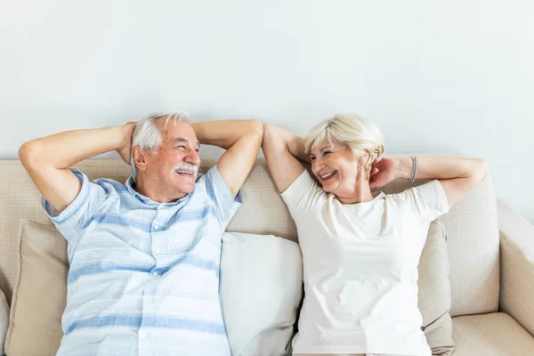 Calm senior mature couple relaxing on soft comfortable sofa having daytime nap together, carefree middle aged old family breathing fresh air enjoying no stress free peaceful weekend resting on couch