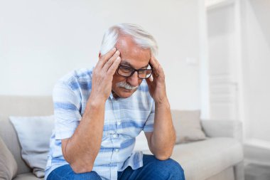 Attack of the monster migraine. Unhappy Retired Senior man holding his head with pain expression . Face of senior man suffering from headache
