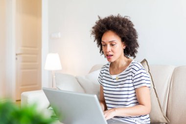 Güzel kadın serbest yazar dizüstü bilgisayarla uzaktan kumandayı planlama projesi için bilgi topluyor. Modern dizüstü bilgisayarda e-posta okurken gülen kız .