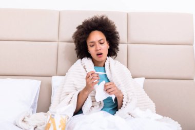 Sickness, seasonal virus problem concept. Woman being sick having flu lying on bed looking at temperature on thermometer. Sick woman lying in bed with high fever. Cold flu coronavirus, covid19
