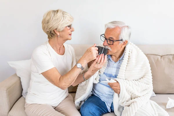 Wife taking care of her sick husband.Senior man having flu. Old people,senior man with winter seasonal illness, fever, cold