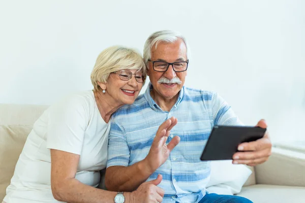 Senior couple using digital tablet at home. Grandparents using social media. Elderly couple together at home retirement concept using digital tablet