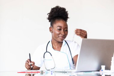 Female doctor in white coat holding blood test tubes in hands while wrapped up in work at modern lab. Female life science professional holding glass cuvette. Healthcare and biotechnology concept.