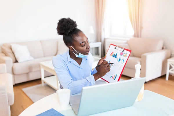 African american businesswoman having video conference while in quarantine during COVID-19 pandemic. Analyzing stock market chart and key performance indicators via video call