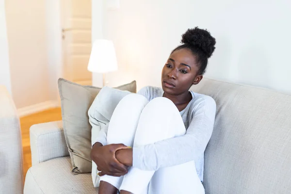 Sad african american woman with depression sitting on sofa. lonely stressed upset young black girl thinking of psychological problem thinking regret about mistake