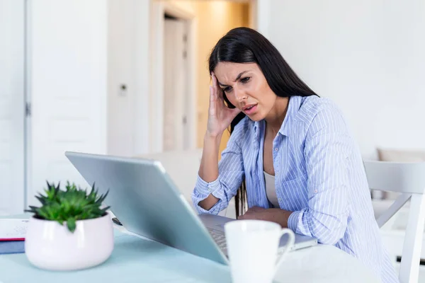 Feeling exhausted. Frustrated young woman looking exhausted while sitting at her working place. Stressed tired businesswoman feels exhausted sitting at office desk with laptop
