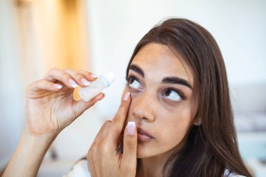 Woman using eye drop. Female dropping eye lubricant to treat dry eye or allergy. Sick girl treating eyeball irritation or inflammation, sick woman suffering from irritated eye, optical symptoms.