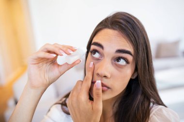 Photo of a woman using eye drop. Female dropping eye lubricant to treat dry eye or allergy. Sick girl treating eyeball irritation or inflammation sick woman suffering from irritated eye, optical symptoms.